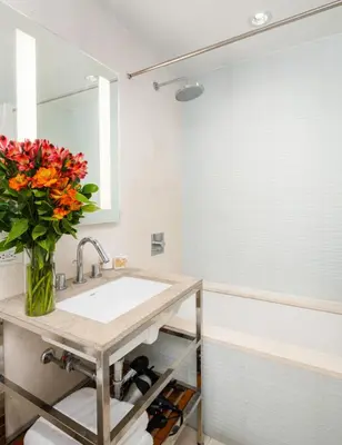 a bathroom with a sink and a vase of flowers at Beautiful 2BD with a Gym near Times Square in New York