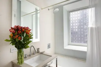 a bathroom with a sink and a vase of flowers at Stylish 1BD near Bryant Park with Washer and Dryer in New York