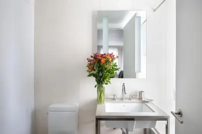 a bathroom with a sink and a vase of flowers at Stylish 1BD near Bryant Park with Washer and Dryer in New York