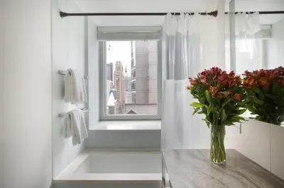 a vase of flowers on a table in front of a window at Beautiful 2BD Apartment near Times Square in New York