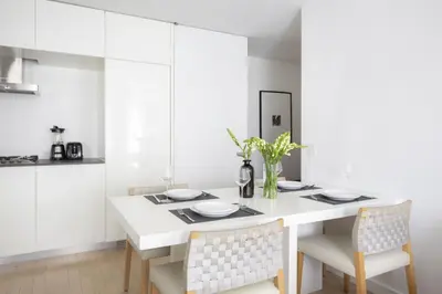a white dining room with a white table and chairs at Modern 2BD in Midtown with Washer and Dryer in-unit in New York