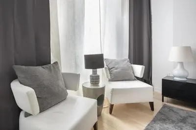 a living room with a white chair and a chair and a lamp at Modern 2BD in Midtown with Washer and Dryer in-unit in New York
