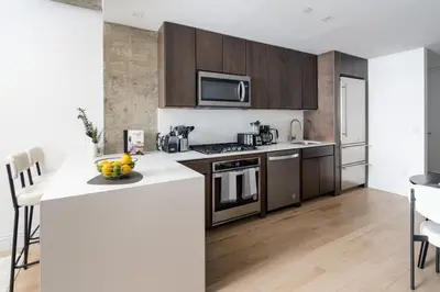 a kitchen with stainless steel appliances and wooden cabinets at Chic and Spacious 2BD Apt with washer and dryer in unit in New York