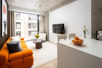 a living room with an orange couch and a tv at Stunning 2BD Penthouse in Chelsea w Washer and Dryer in New York