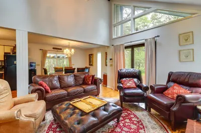a living room with leather furniture and a large window at Fire Pit, Kayaks and Hammocks Long Pond Home! in Long Pond