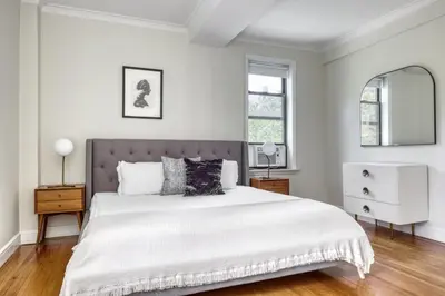 a white bedroom with a large bed and a mirror at Upper W Side 1BR w Gym by Lincoln Sq NYC-331 in New York