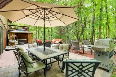 a patio with a table and chairs and an umbrella at Game Room and Hot Tub Ski Getaway in Poconos! in East Stroudsburg