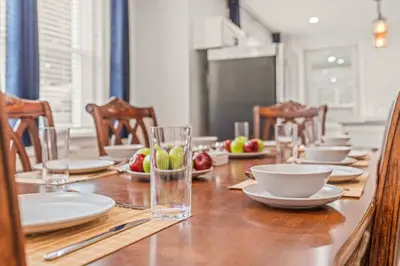 a long wooden table with plates and bowls and glasses at King Bed Gym Parking AC Train in Narberth