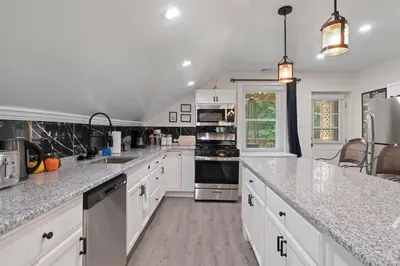a kitchen with white cabinets and granite counter tops at 5 Star Penthouse King Deck AC Train in Narberth