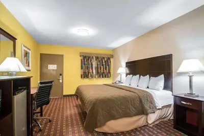 a hotel room with a large bed and yellow walls at Rodeway Inn Towanda in Towanda