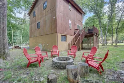 a group of red chairs around a fire pit in front of a building at Cozy Chalet Game Rm and Fireplace in East Stroudsburg