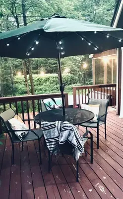a table and chairs on a deck with an umbrella at Chalet Retreat w/ Hot Tub, Short Walk to Lake & Pool in Jim Thorpe