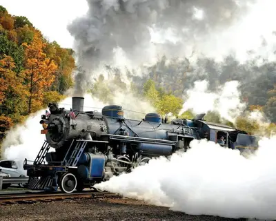 a steam engine train on tracks with smoke at Chalet Retreat w/ Hot Tub, Short Walk to Lake & Pool in Jim Thorpe
