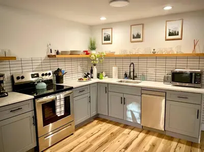 a kitchen with stainless steel appliances and wooden floors at Chalet Retreat w/ Hot Tub, Short Walk to Lake & Pool in Jim Thorpe