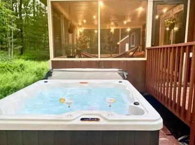 a hot tub on a porch with two wine glasses at Chalet Retreat w/ Hot Tub, Short Walk to Lake & Pool in Jim Thorpe