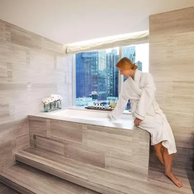 a woman sitting on a bath tub in a bathroom at Park Hyatt New York in New York