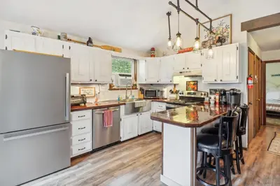 a kitchen with white cabinets and a wooden floor at Tobyhanna Home with Fire Pits - 9 Mi to Kalahari! in Tobyhanna