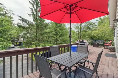 a picnic table with a red umbrella on a deck at Tobyhanna Home with Fire Pits - 9 Mi to Kalahari! in Tobyhanna