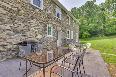 a patio with a table and chairs in front of a stone building at Large Historic Home in Pennsylvania Dutch Country! in Coatesville