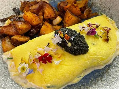 a plate of food with a omelet and potatoes at The Frogtown Inn in Canadensis