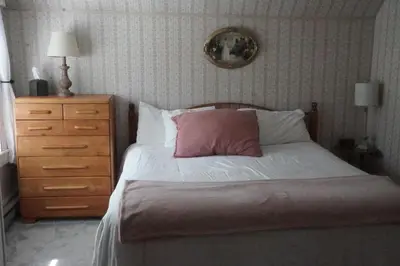 a bedroom with a bed with a pink pillow and a dresser at The Frogtown Inn in Canadensis
