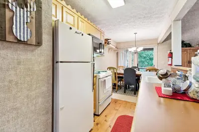 a kitchen with a refrigerator and a dining room at Lake Harmony Home with Screened Porch and Hot Tub! in Lake Harmony