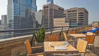 a balcony with tables and chairs and a city skyline at ROOST Midtown in Philadelphia