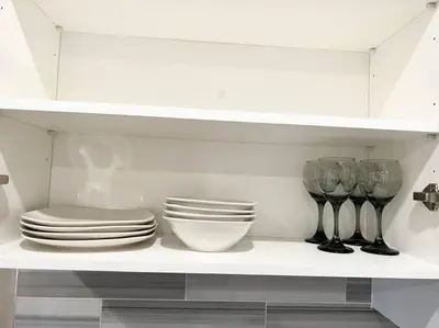a white shelf with plates and bowls and wine glasses at 508 Urban Lifestyle king bed APT in Center CITY in Philadelphia