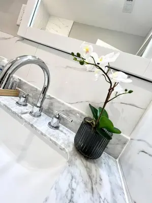 a vase with white flowers sitting on a sink at 308 Cozy and warm King Bed APT in center city in Philadelphia