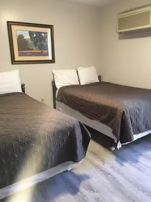 two beds sitting next to each other in a room at All Suites Inn Budget Host in Lewisburg