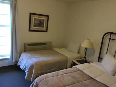 a hotel room with two beds and a window at All Suites Inn Budget Host in Lewisburg