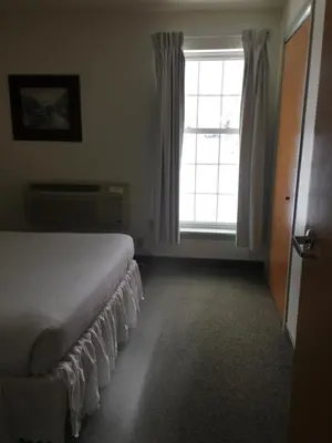 a bedroom with a bed and a large window at All Suites Inn Budget Host in Lewisburg