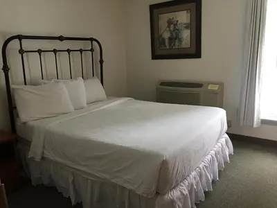 a bedroom with a large bed with white sheets and pillows at All Suites Inn Budget Host in Lewisburg