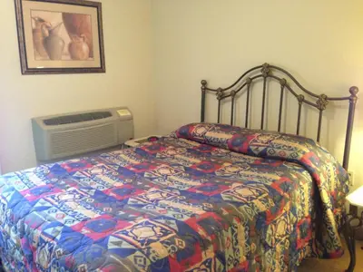 a bedroom with a bed with a colorful comforter and a fan at All Suites Inn Budget Host in Lewisburg