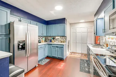 a kitchen with blue cabinets and a stainless steel refrigerator at A Time to Remember Home in Tobyhanna with Pool! in Tobyhanna