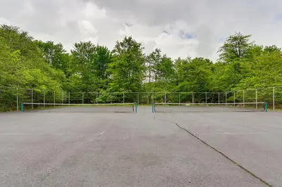 a tennis court with a net in front of trees at A Time to Remember Home in Tobyhanna with Pool! in Tobyhanna