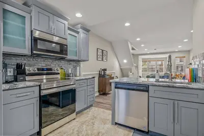 a large kitchen with stainless steel appliances and gray cabinets at Uptown Gem! Immaculate-Comfort-Character! in Philadelphia
