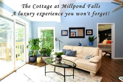 a living room with a couch and a glass table at Luxury Cottage at Millpond Falls in Warwick