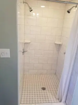 a bathroom with a shower with a white tiled shower at Luxury Cottage at Millpond Falls in Warwick