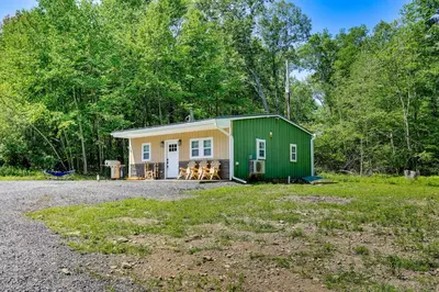 a green and yellow cottage in the woods at Secluded Poconos Cabin 75 Acres and Fire Pit! in East Stroudsburg