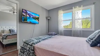 a bedroom with a bed and a tv on the wall at Luxury Lake Front Camelot Villa in Pocono Lake