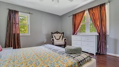 a bedroom with a bed and a dresser and two windows at Luxury Lake Front Camelot Villa in Pocono Lake