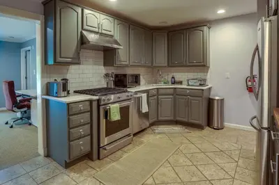 a kitchen with brown cabinets and a stove top oven at Charming Monroe Township Home - 13 Mi to RU! in East Brunswick