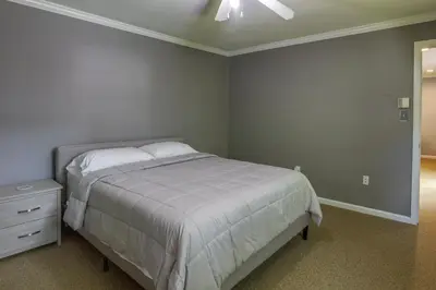 a bedroom with a white bed and a night stand at Charming Monroe Township Home - 13 Mi to RU! in East Brunswick