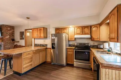 a kitchen with wooden cabinets and a stainless steel refrigerator at Pocono Chalet - Hot Tub - Game Room in Albrightsville