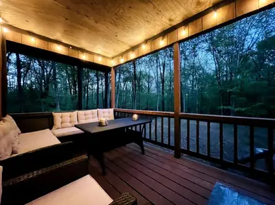 a screened in porch with a couch and a table at Pocono Chalet - Hot Tub - Game Room in Albrightsville