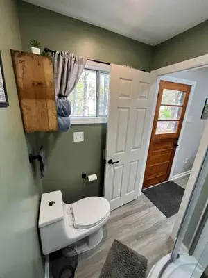 a bathroom with a white toilet and a door at Wally's Cottage in Hawley