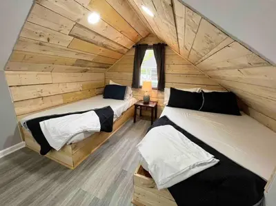 two beds in a room with wooden walls at Wally's Cottage in Hawley