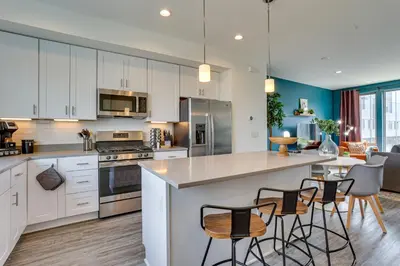 a kitchen with white cabinets and a island with bar stools at 3 Mi to Center City Philadelphia Townhome in Philadelphia
