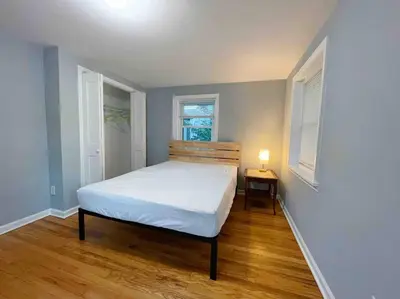 a bedroom with a bed and a table and two windows at THE ECO HOME. Entire place with private parking in Wilmington